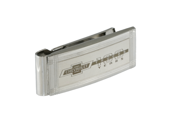 Silver money clip with engraved Chevrolet logo and "100 years" text, set against a black background. The clip conveys a sleek, classic design.